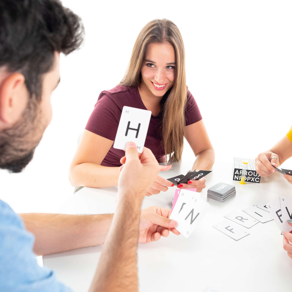 friends having fun playing yigo game trying to form words enjoying a vocabulary and spelling card game for teenagers and adults